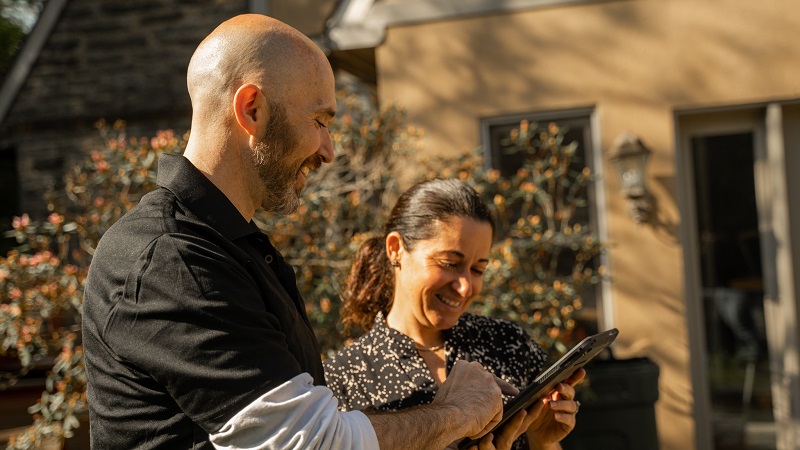 a man from junk removal service provider holding a tablet and explaining to his women client about the mattress disposal guide